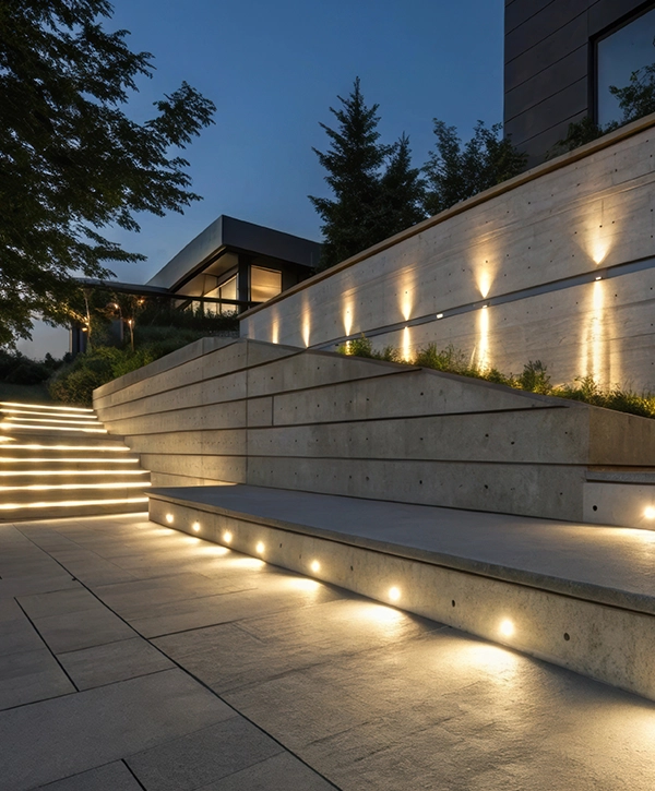 Contemporary landscape design featuring a concrete retaining wall with integrated lighting