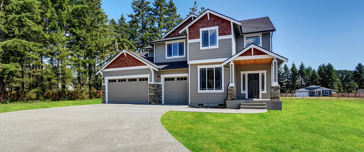 New concrete driveway leading to modern suburban home with stone accents and triple garage