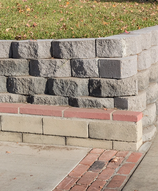 Residential retaining wall featuring a variety of stacked blocks and mortared brick textures